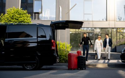 Driver or concierge helps a business couple carry their suitcases to minivan taxi from hotel. Concept of business travel and transportation service